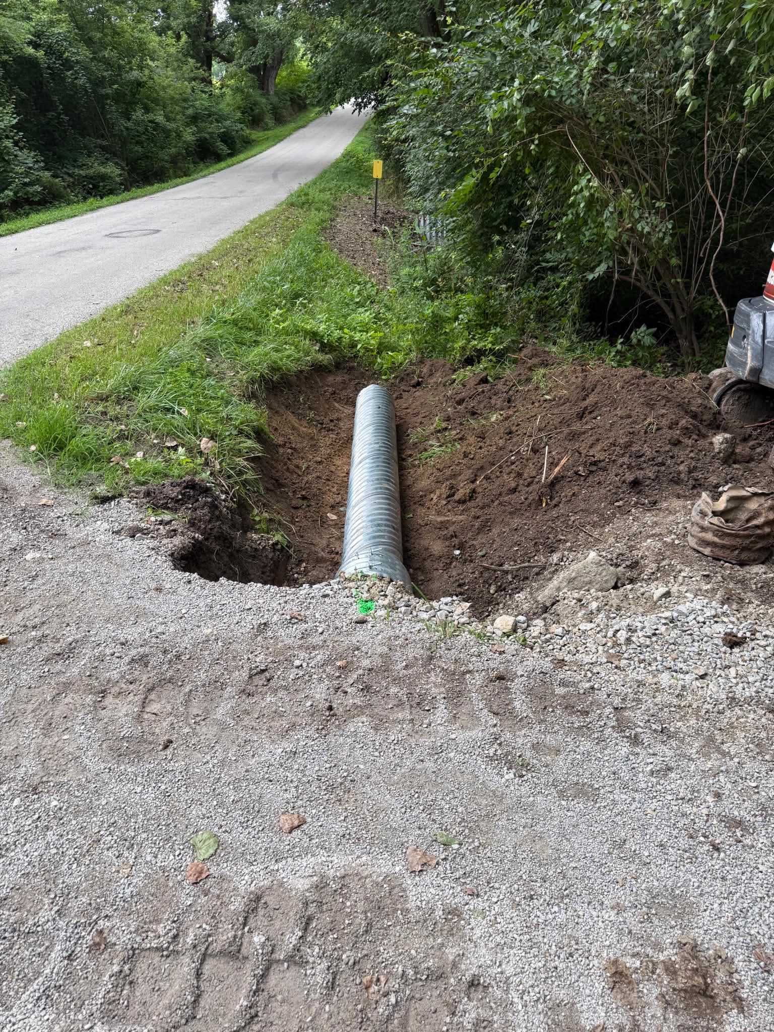 A new galvanised culvert pipe bedded in a roadside ditch