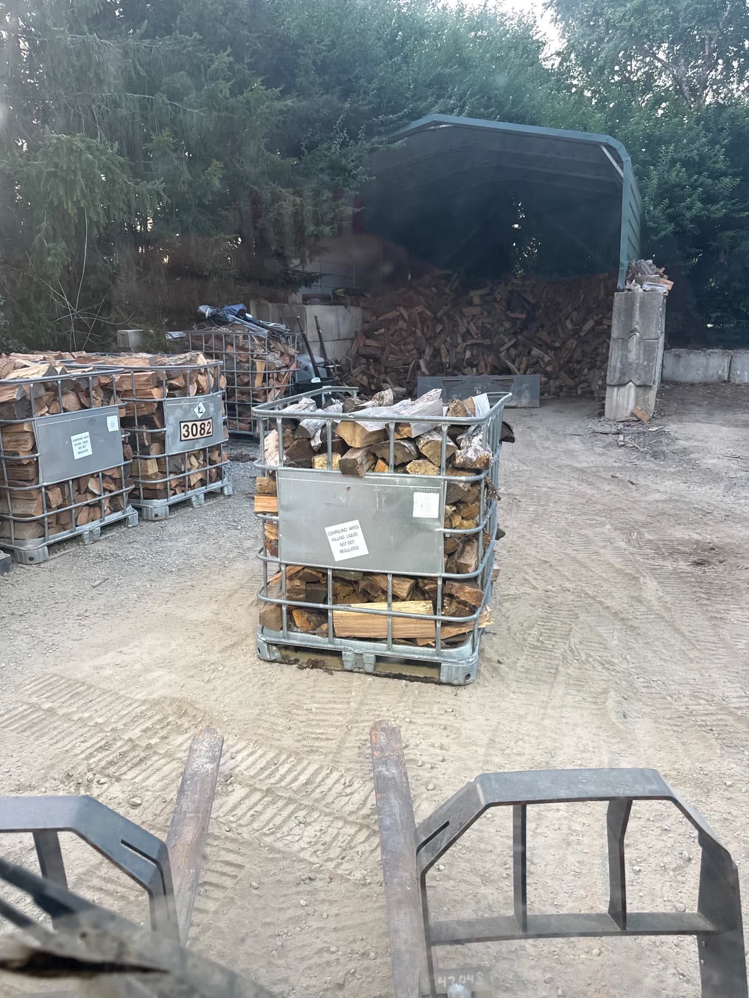 Split firewood stacked in galvanised totes at the yard